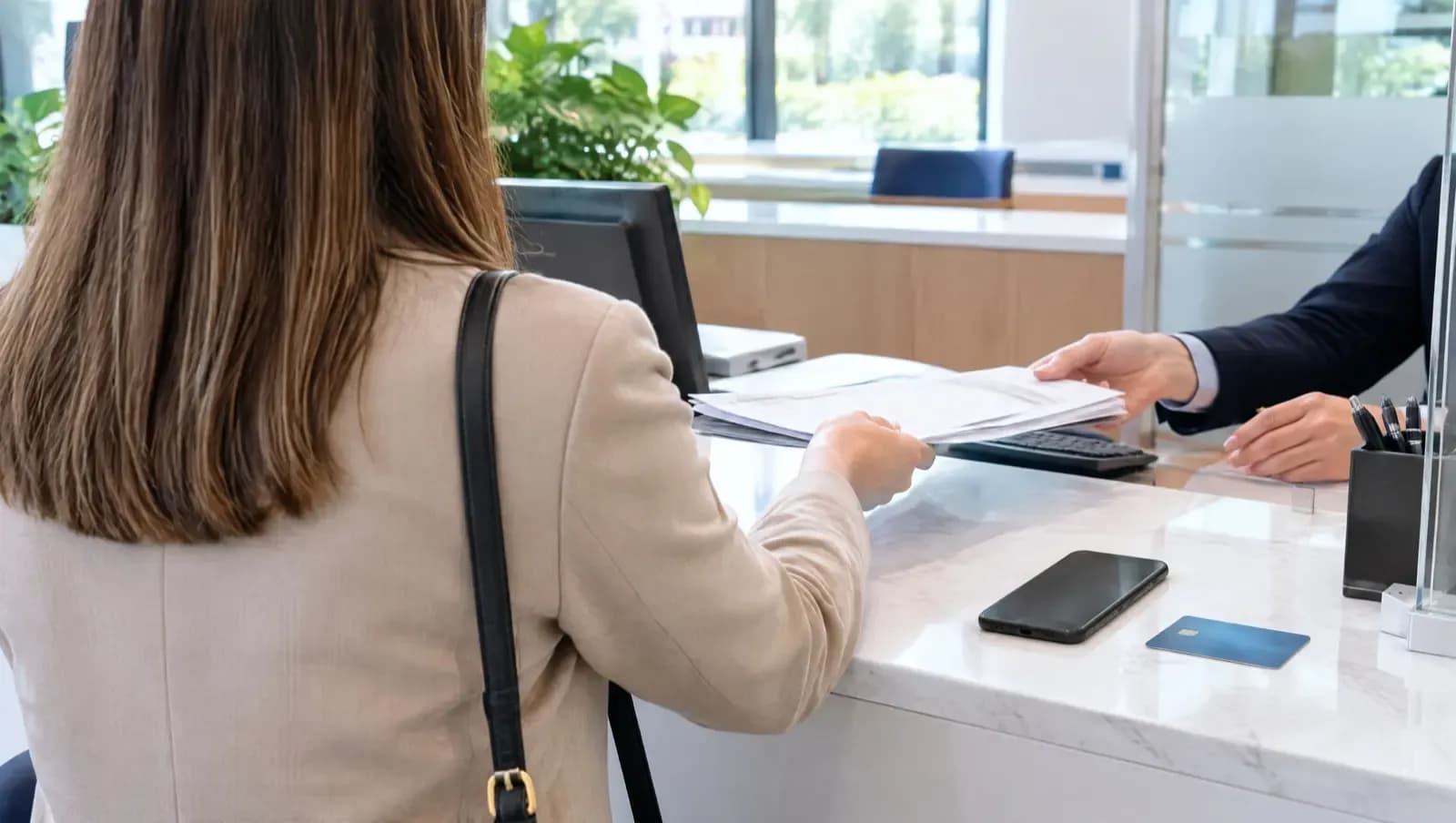 Załatwianie formalności przy okienku – dokumenty, telefon i karta płatnicza na ladzie